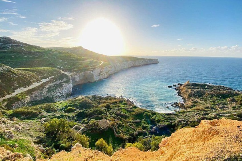 A coastal landscape with cliffs, greenery, and a clear sky. 3