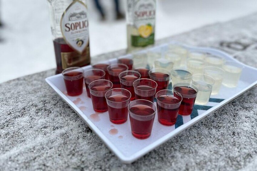 Una bandeja con vasos exprés de líquidos rojos y transparentes, posiblemente alcohol, sobre una superficie de piedra. 5