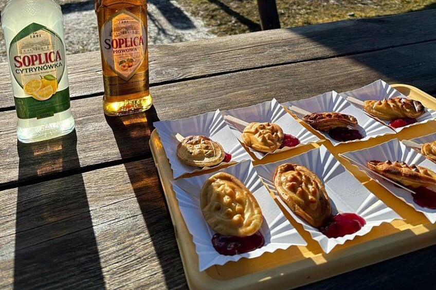 A wooden table with pastries and bottles of Soplca vodka. 2