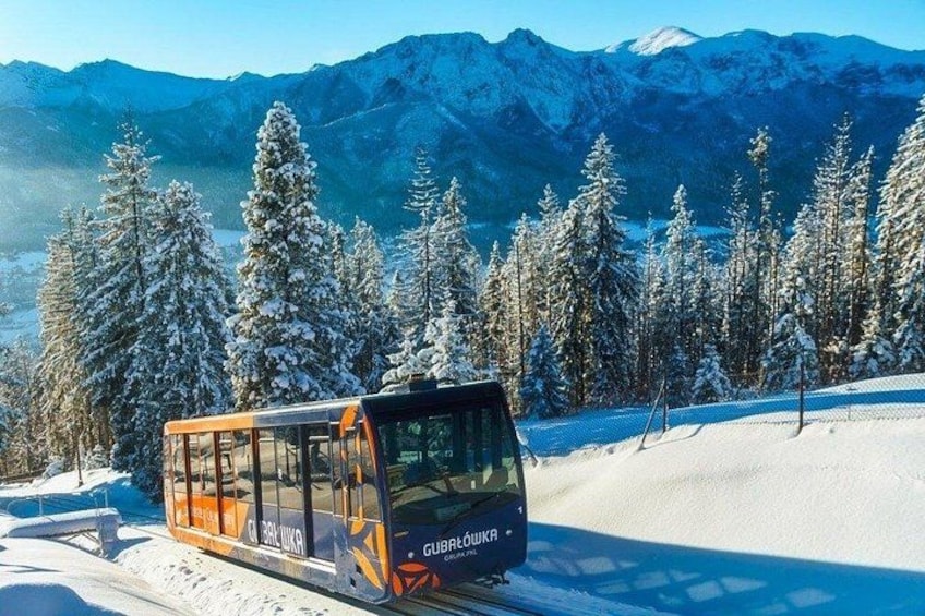 A cable car on a snowy mountain with snow-covered trees and mountains in the background. 5