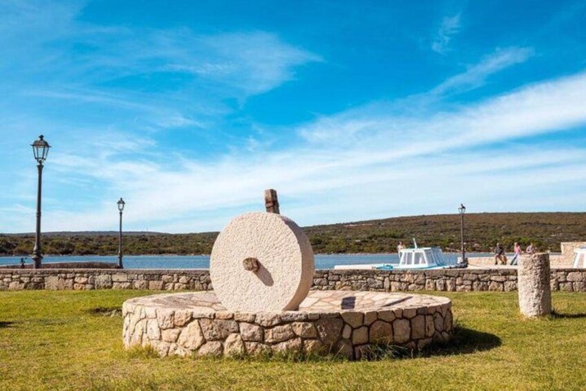 A stone structure with a circular design, a stone wall, and a body of water in the background. 3