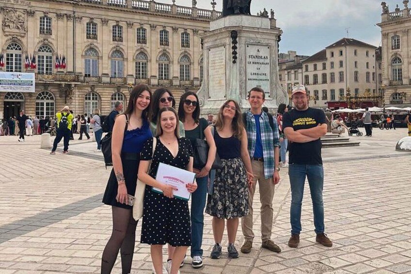 A group of people standing in a public square with historical buildings in the background. 5