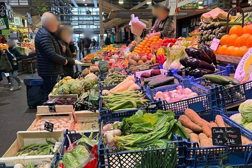 A bustling indoor market with various fresh produce displayed in bins and crates. 3