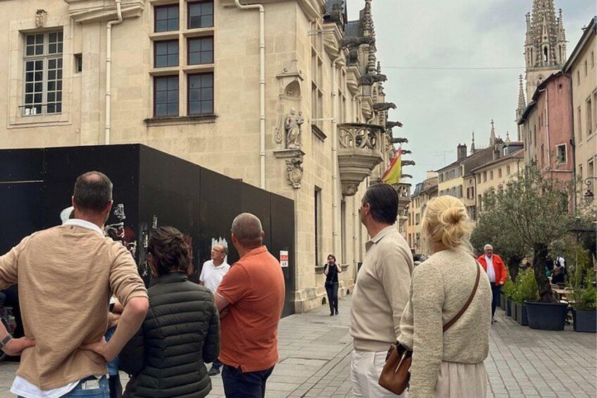 A group of people standing on a cobblestone street in front of a historic building with ornate architecture. 3