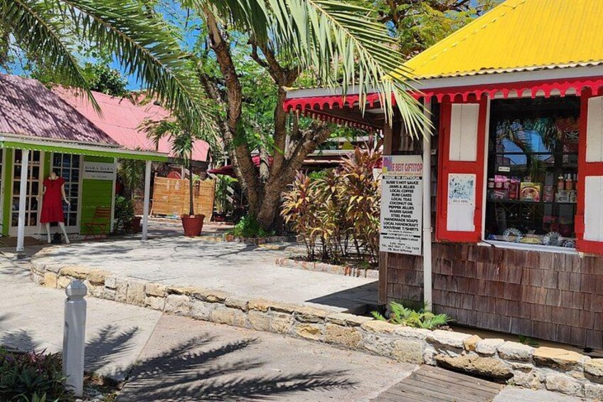 Una pequeña tienda con techo rojo y amarillo, rodeada de palmeras y un sendero de piedra. 4