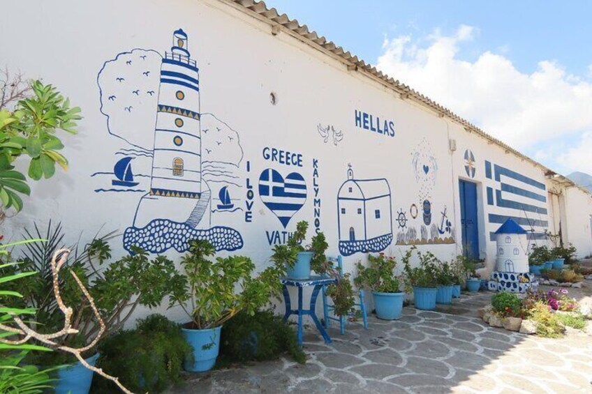 A mural with a lighthouse, sailboats, and potted plants on a building wall. 4
