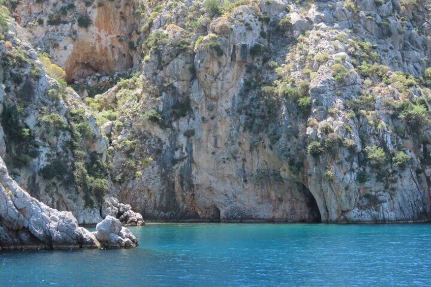A rocky coastline with a clear blue sea and a cave entrance. 5