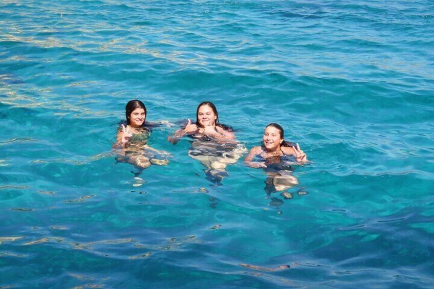 Three people swimming in clear blue water. 3