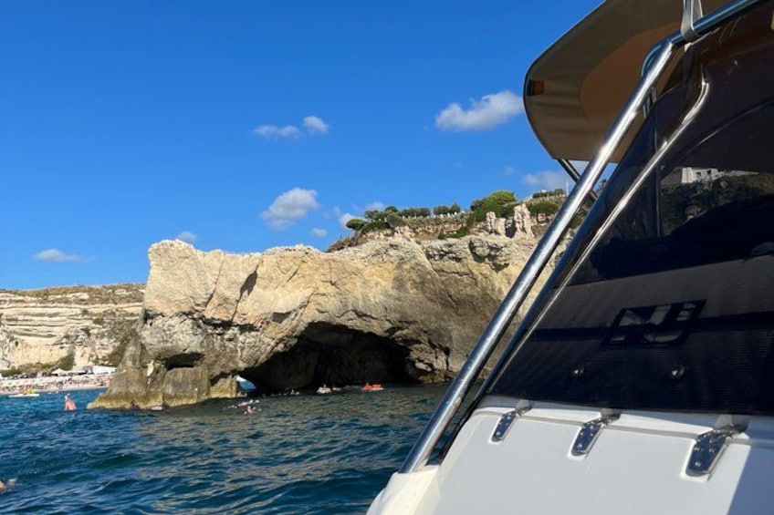 A rocky coastline with a boat in the foreground and a cave entrance. 2