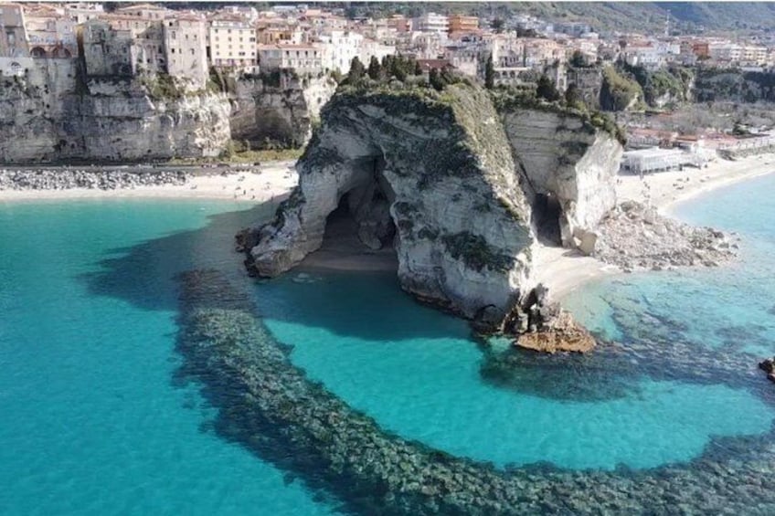 A coastal town with a prominent rock formation and clear turquoise waters. 5