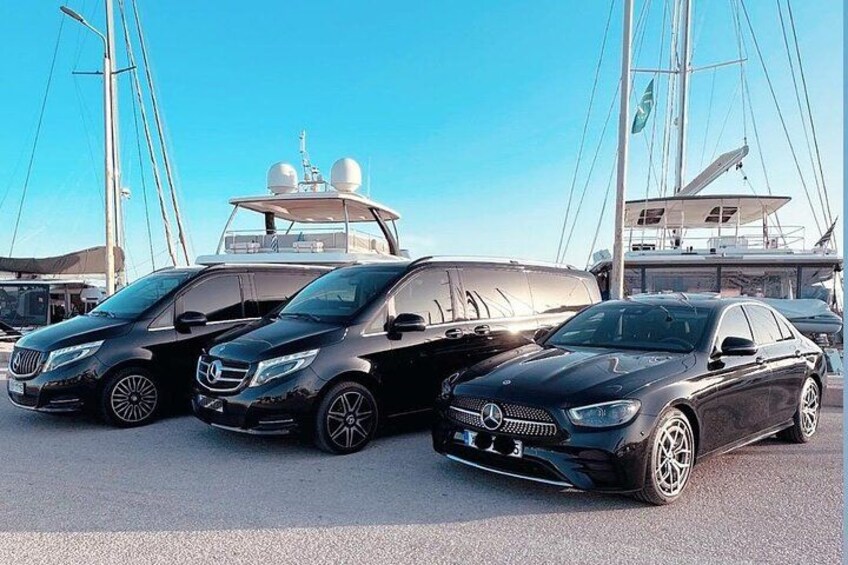 Tres coches negros Mercedes-Benz estacionados en una marina, con veleros al fondo. 5