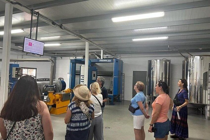 A group of people in an industrial setting with large cylindrical tanks and machinery. 5