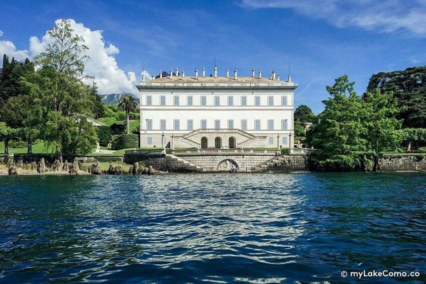 A large white building with a symmetrical facade, a central entrance with columns, and a surrounding water body. 5