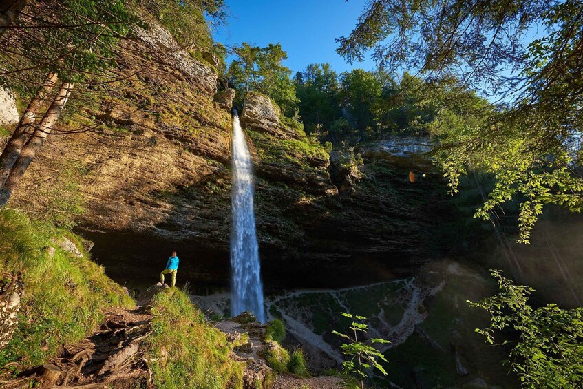 A waterfall cascading down a rocky cliff surrounded by lush greenery. 2