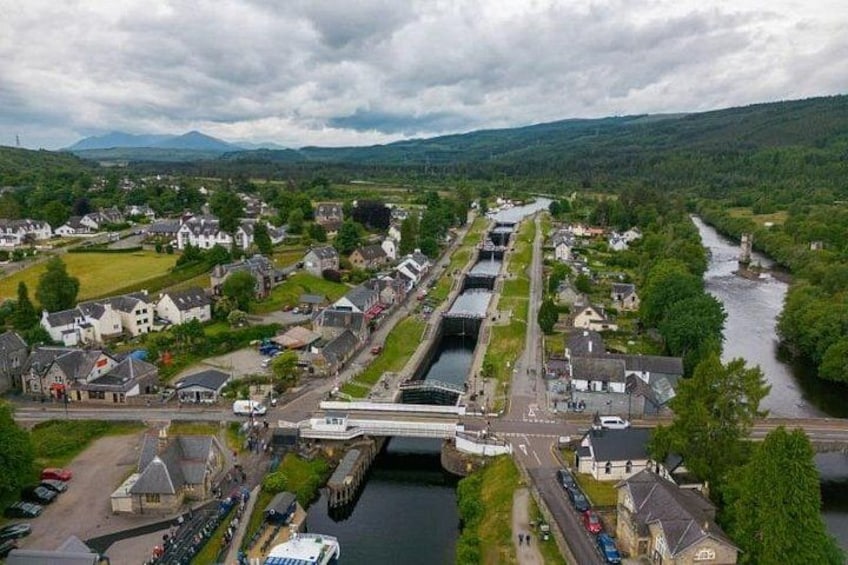 A river flowing through a town with a bridge, houses, and a road. 4