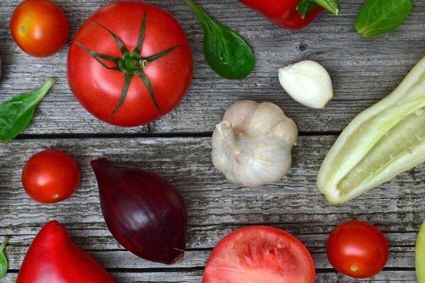 Diverse groenten, waaronder tomaten, knoflook en aubergines, op een houten ondergrond. 4