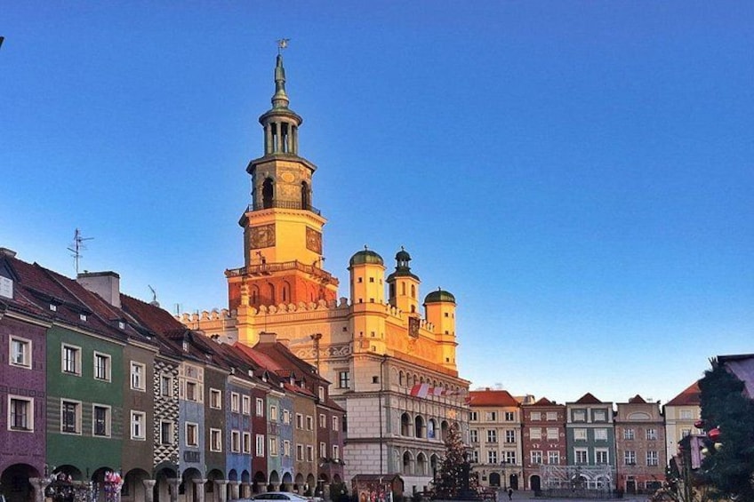 A historic building with a prominent tower and domes, surrounded by colorful buildings. 2