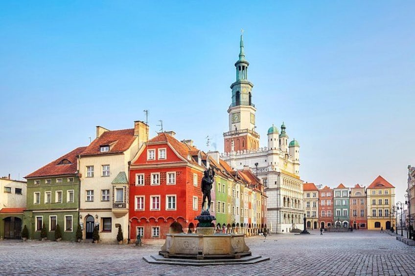 A cobblestone square with colorful historic buildings, a prominent tower, and a fountain. 3