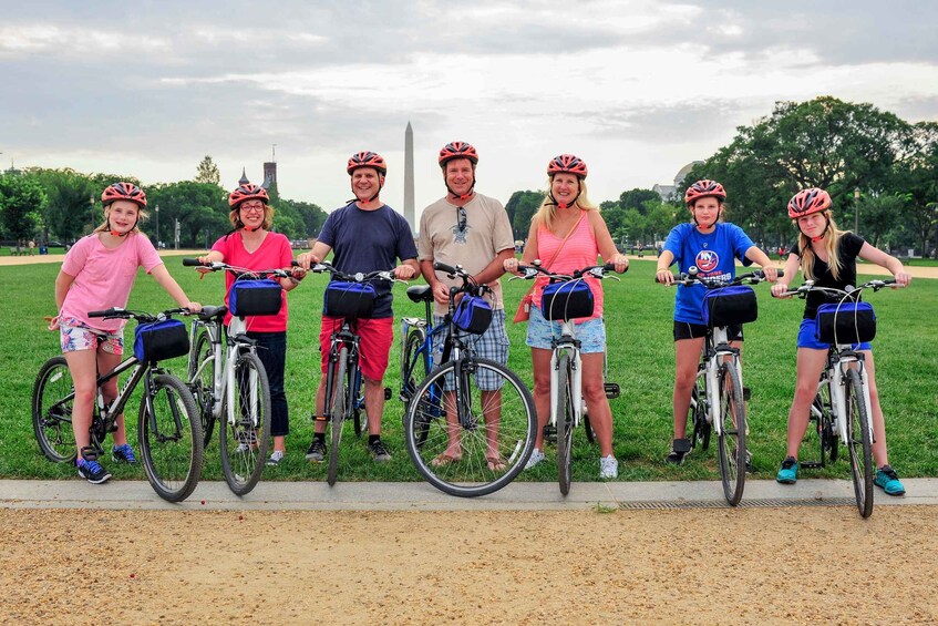Un grupo de personas en bicicleta en un parque, con un monumento grande al fondo. 5