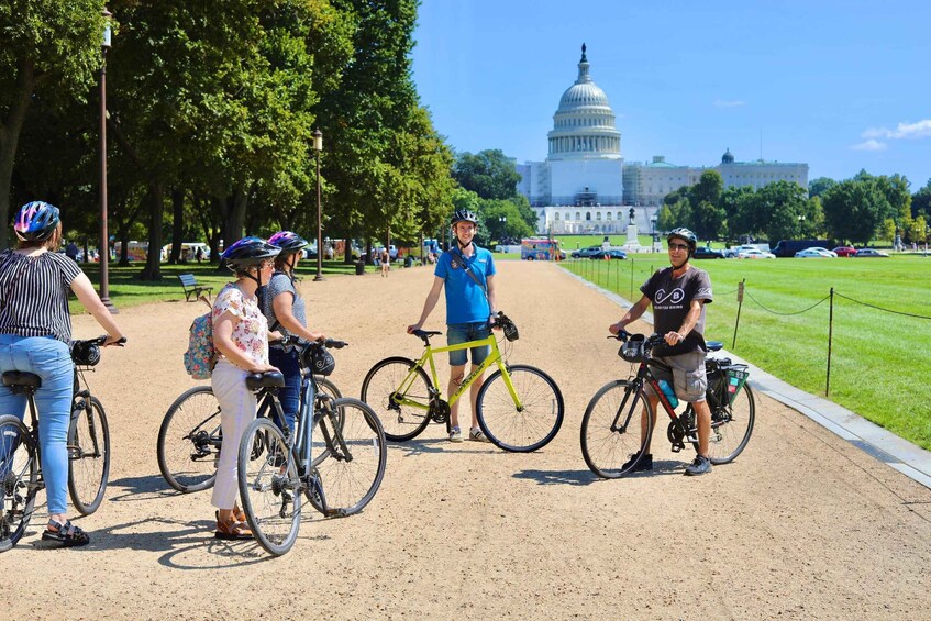 Personas en bicicleta en un parque, con un edificio grande al fondo. 2