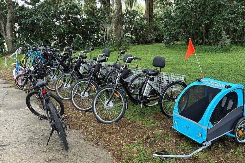 Une rangée de vélos est stationnée sur un chemin, avec une remorque bleue pour enfant attachée à l’un d’eux. 2