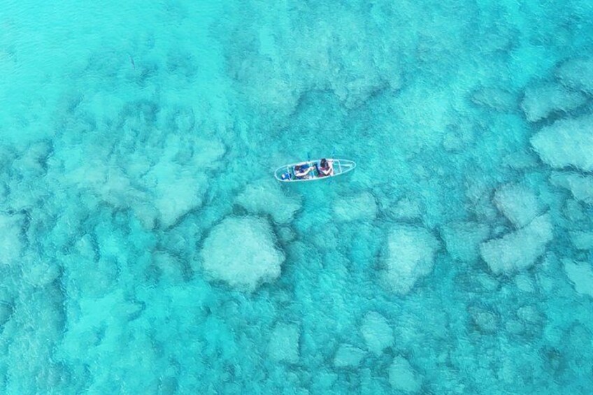 A person kayaking on turquoise water with coral formations. 2