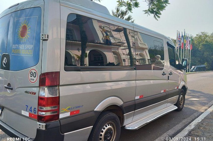 A silver van parked on a street with a blue sign on the back, a step rail, and a license plate number 746. 3