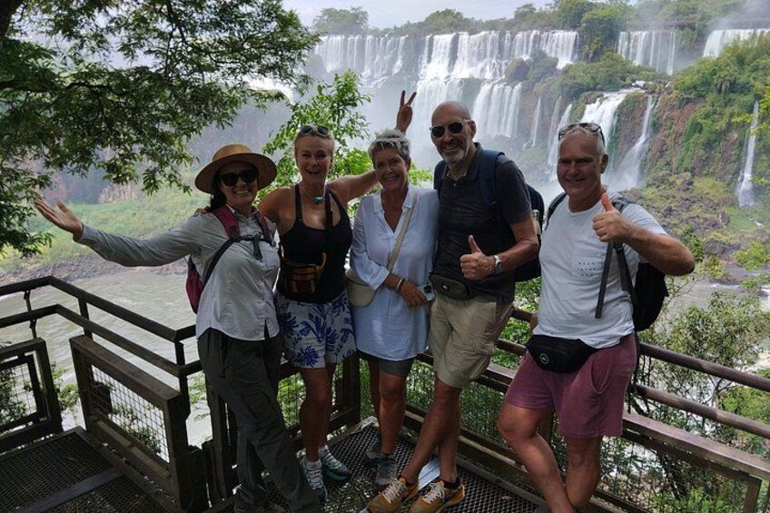 A group of people standing on a bridge with a waterfall in the background. 4