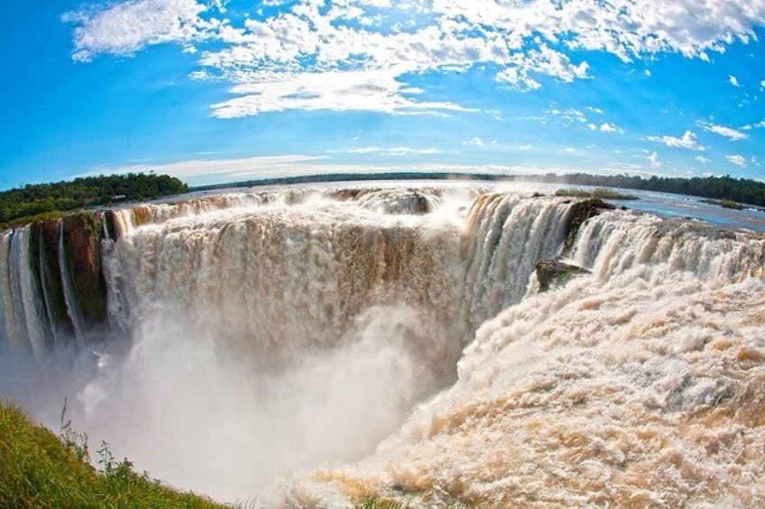 A large waterfall with multiple cascades, surrounded by greenery and a clear blue sky. 2