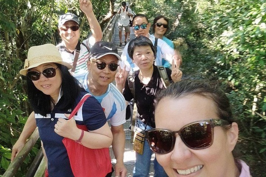 A group of people walking on a bridge surrounded by greenery. 3