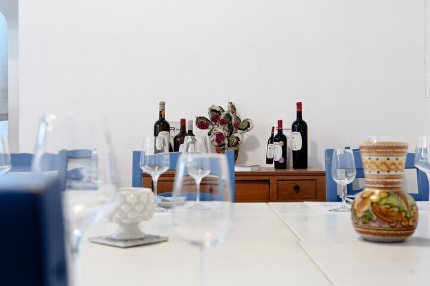 Une table à manger dressée avec des verres à vin, des bouteilles et un vase décoratif. 1