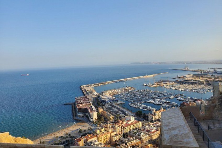 Un paisaje urbano costero con un puerto deportivo, edificios y un muelle largo que se adentra en el mar. 3