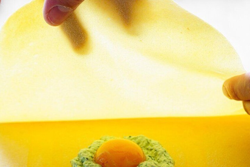 A hand holding a yellow object over a green surface with a round orange item on it. 2