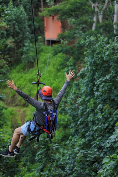 A person zip-lining through a forested area with outstretched arms. 3