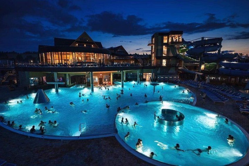 A large outdoor swimming pool with multiple water slides and a building in the background. 4