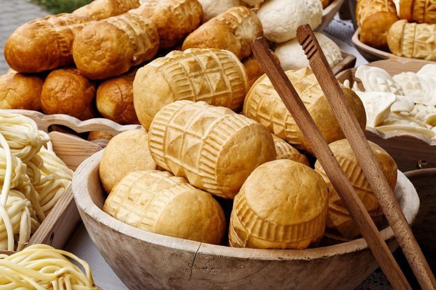 A variety of baked goods including bread rolls and pastries in a wooden bowl. 2