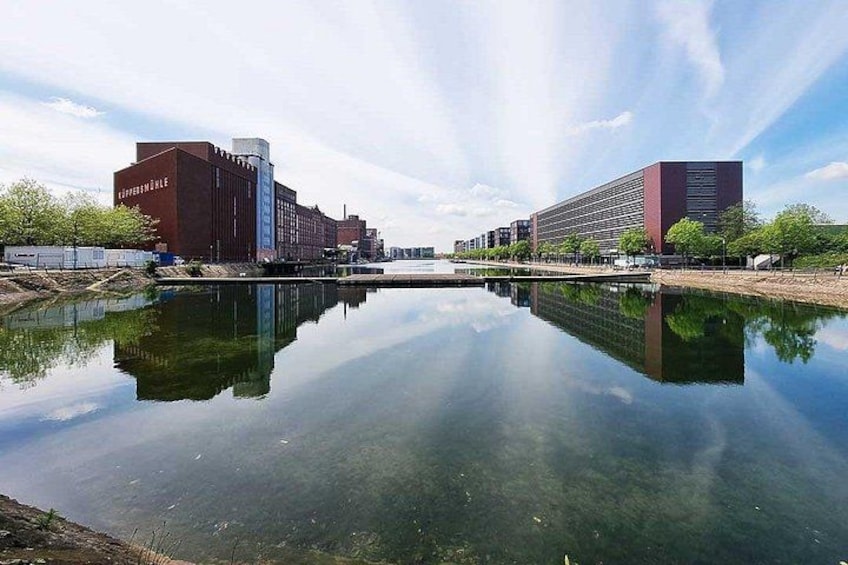 A river reflecting buildings, a bridge, and a clear sky. 1