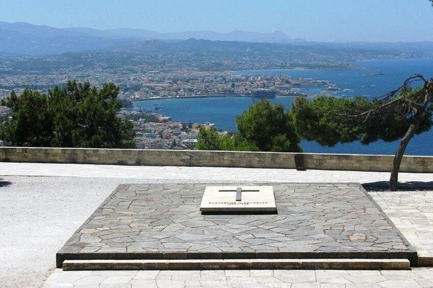 A stone platform with a plaque, overlooking a coastal cityscape with mountains in the distance. 5