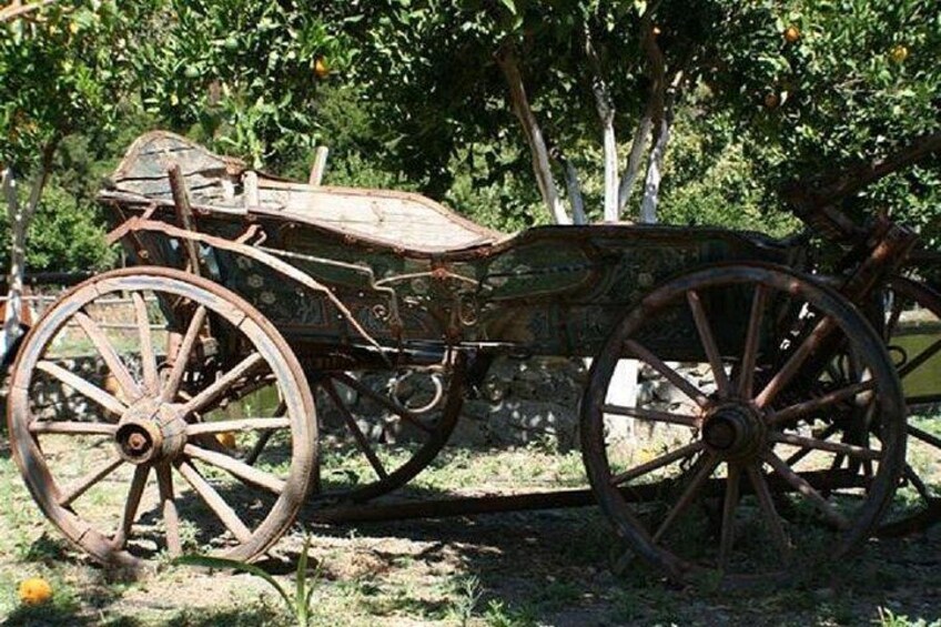 An old wooden cart with large wheels, parked outdoors. 4