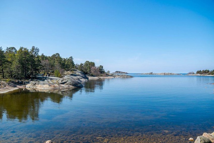 A calm lake surrounded by trees and rocky shores. 5