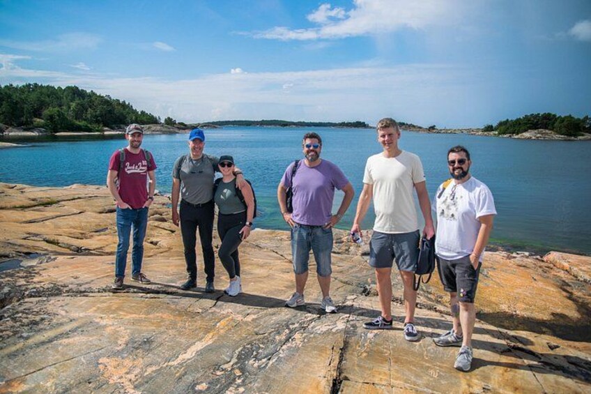 A group of people standing on rocky terrain by a body of water with a clear sky. 3