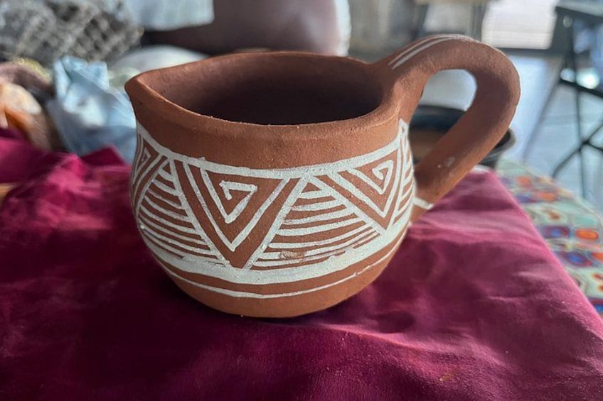 A ceramic mug with geometric patterns on a red fabric surface. 3