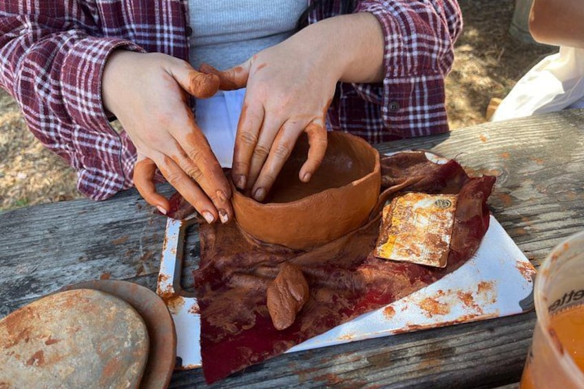 A person preparing food outdoors, using a wooden bowl and a cutting board with meat and cheese. 5