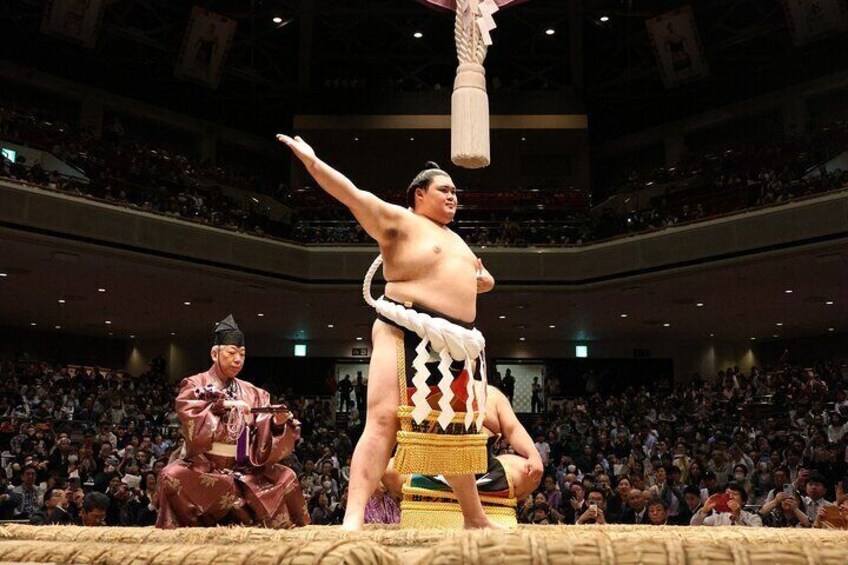 A sumo wrestler performing a ritual at a wrestling event. 4