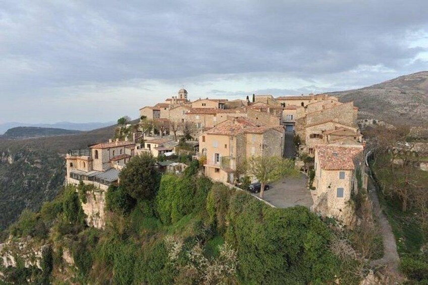 Un borgo collinare con edifici in pietra e un sentiero tortuoso. 1