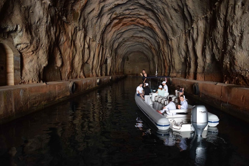 A boat in a narrow, rocky tunnel with people on board. 2