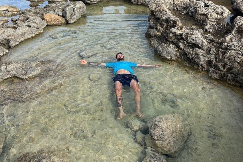 A person floating in clear water surrounded by rocks. 2
