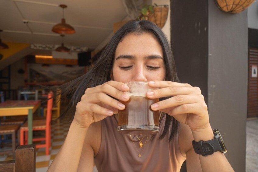 A person sitting indoors, holding a clear glass. 3