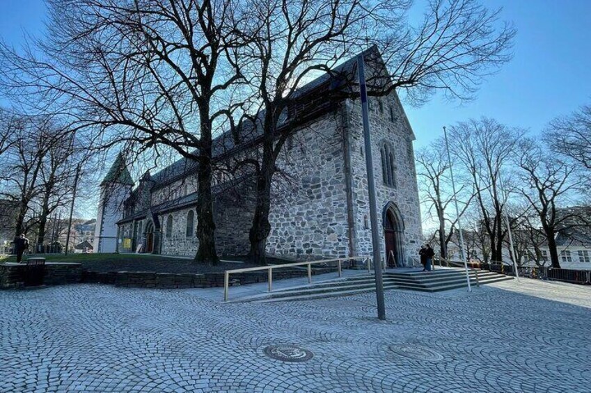 A stone church with a cobblestone courtyard and leafless trees. 3
