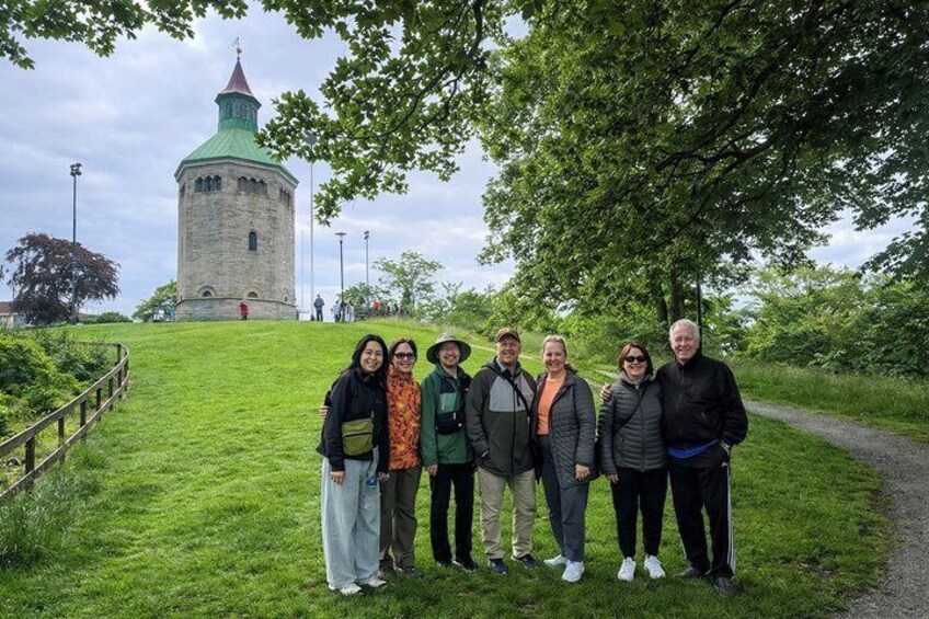 A group of people standing on a grassy hill with a historic tower in the background. 4